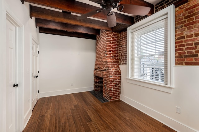 interior space with beam ceiling, dark wood-type flooring, a brick fireplace, and ceiling fan