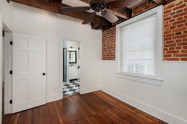 unfurnished bedroom with beamed ceiling, brick wall, dark tile patterned flooring, and ceiling fan