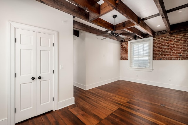 spare room featuring brick wall, beam ceiling, ceiling fan, and dark wood-type flooring