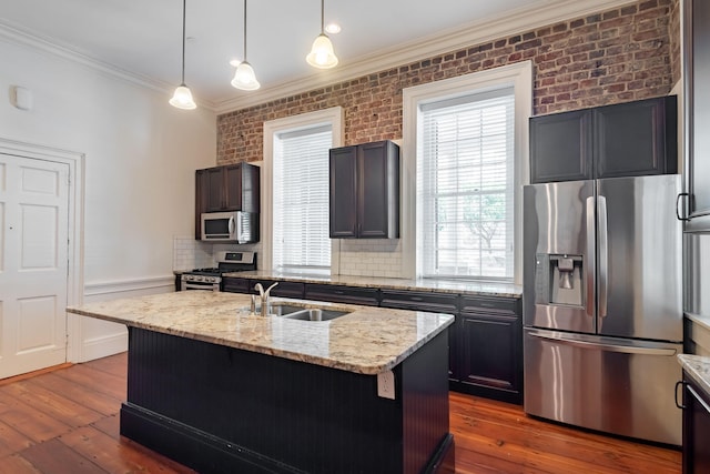 kitchen with dark hardwood / wood-style floors, hanging light fixtures, appliances with stainless steel finishes, and an island with sink