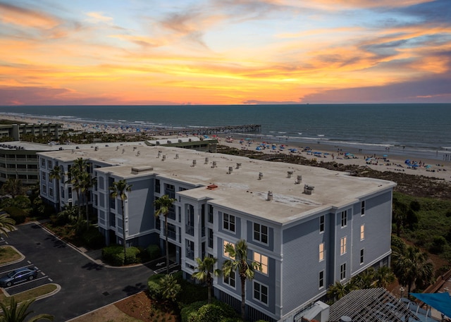 aerial view at dusk with a view of the beach and a water view