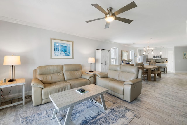 living room with baseboards, ornamental molding, light wood-style floors, and ceiling fan with notable chandelier