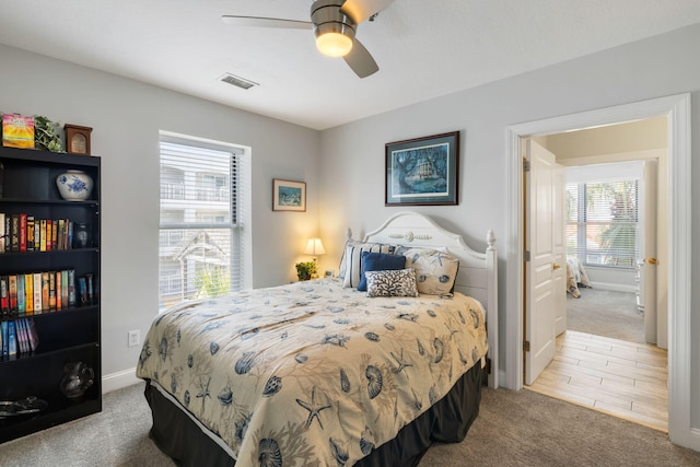 carpeted bedroom featuring baseboards, multiple windows, a ceiling fan, and visible vents