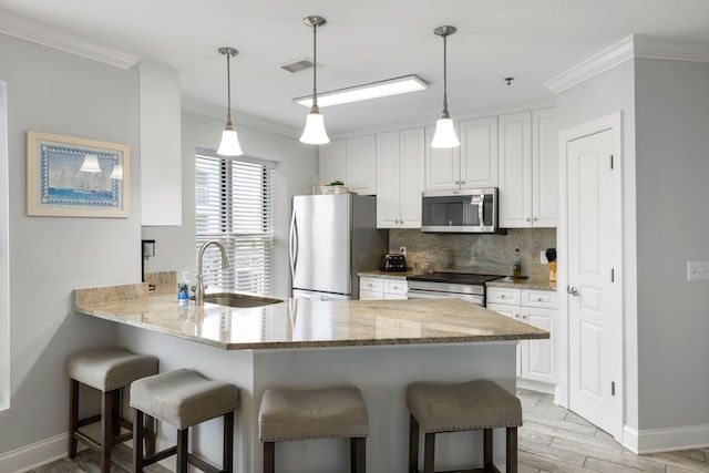 kitchen with tasteful backsplash, a sink, stainless steel appliances, a kitchen bar, and ornamental molding