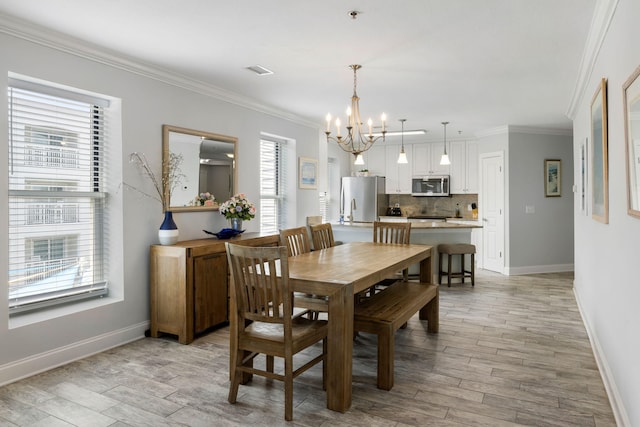 dining area featuring an inviting chandelier, baseboards, crown molding, and a healthy amount of sunlight