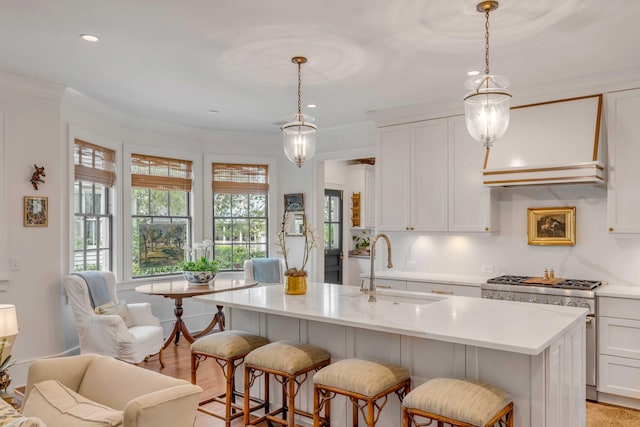 kitchen featuring pendant lighting, white cabinetry, a center island with sink, and sink