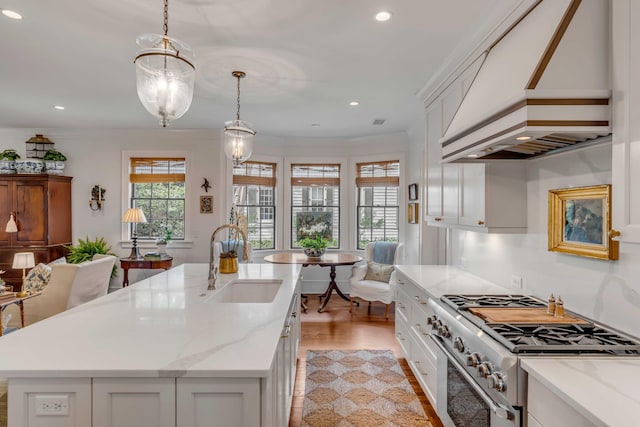 kitchen with high end stainless steel range oven, white cabinetry, and sink