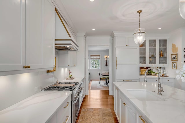 kitchen featuring light stone counters, light hardwood / wood-style floors, white cabinets, stainless steel stove, and decorative light fixtures