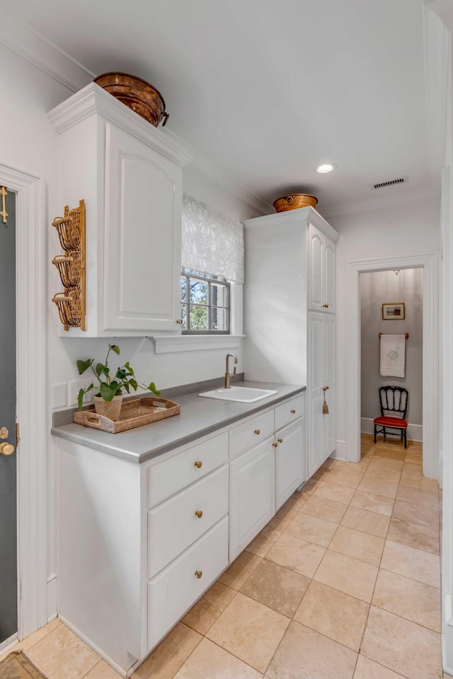 kitchen featuring ornamental molding, white cabinetry, light tile patterned flooring, and sink