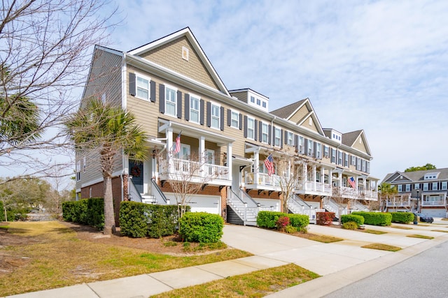 townhome / multi-family property with brick siding, stairs, covered porch, driveway, and an attached garage