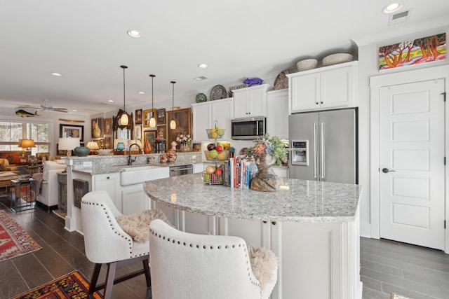 kitchen with visible vents, a kitchen island, a peninsula, stainless steel appliances, and open floor plan