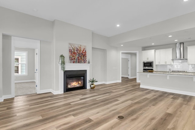 unfurnished living room with sink and light wood-type flooring