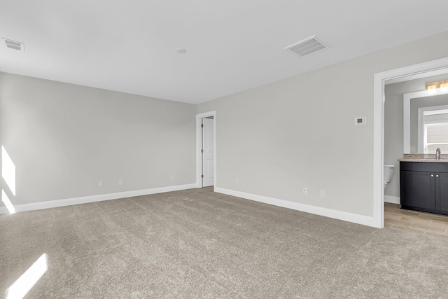 unfurnished room featuring sink and light carpet