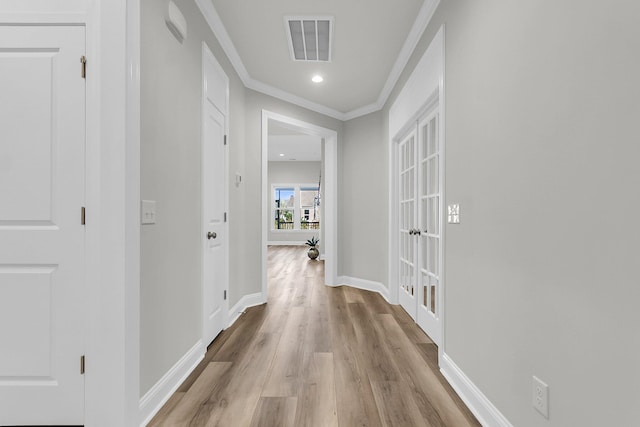 corridor with crown molding, light hardwood / wood-style floors, and french doors