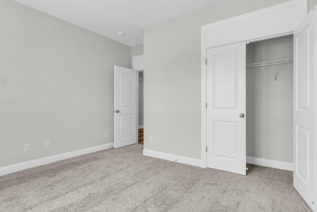 unfurnished bedroom featuring light colored carpet and a closet