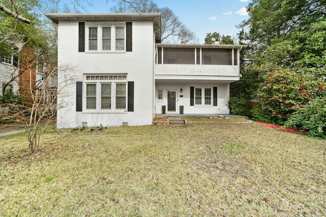 view of front of home featuring brick siding, a front lawn, and a sunroom