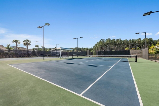 view of tennis court with community basketball court and fence