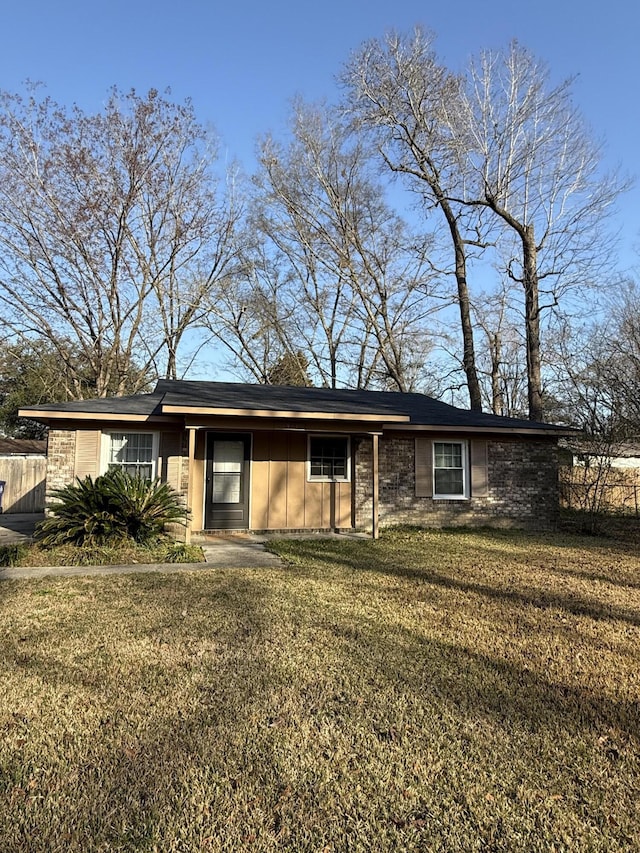 ranch-style home featuring board and batten siding, a front yard, and fence