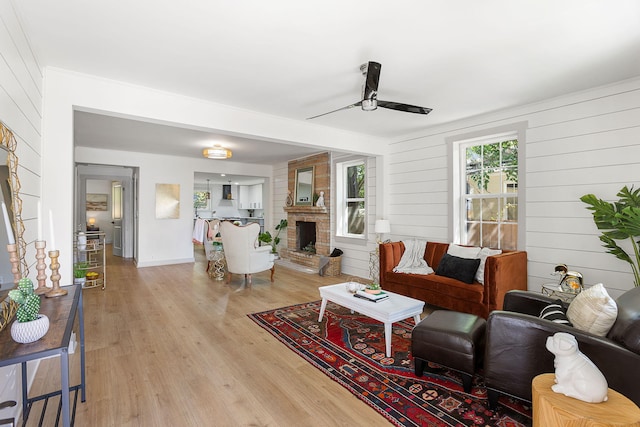 2957 Alabama Dr, North Charleston, SC 29405 - living area with a brick fireplace, baseboards, ceiling fan, wooden walls, and light wood finished floors
