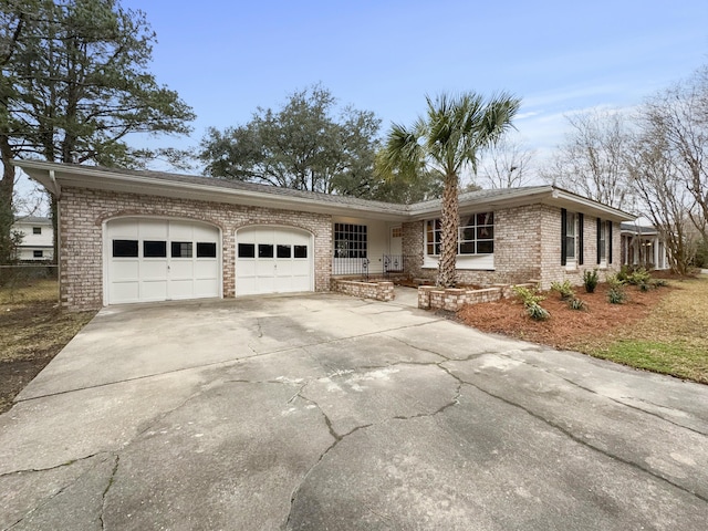 ranch-style home featuring driveway, brick siding, an attached garage, and fence