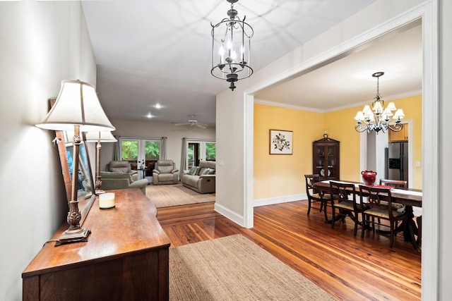 living room with ceiling fan with notable chandelier, ornamental molding, and hardwood / wood-style floors