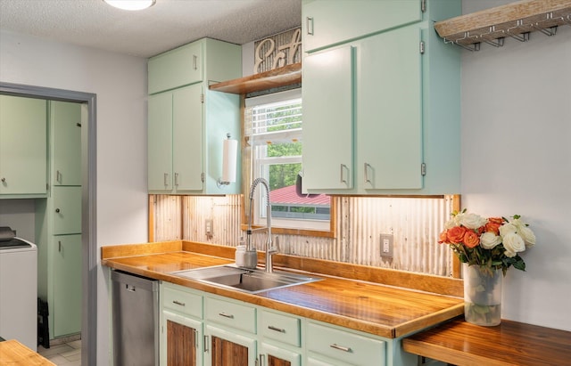 kitchen featuring a sink, dishwasher, washer / clothes dryer, and a textured ceiling