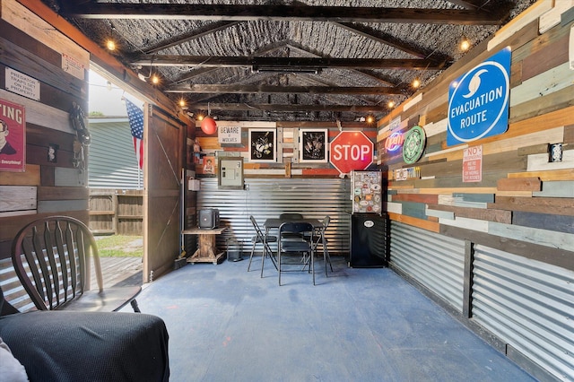 miscellaneous room with concrete flooring, wood walls, and vaulted ceiling