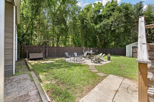 view of yard featuring an outdoor fire pit, a patio area, a storage unit, and an outbuilding