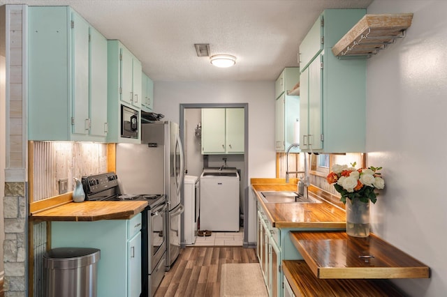 kitchen with electric range, wood counters, a sink, independent washer and dryer, and light wood-style floors