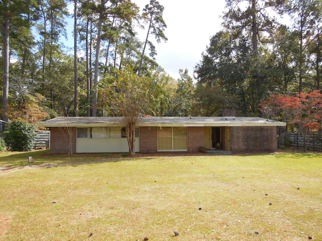 rear view of property with a yard, fence, and brick siding