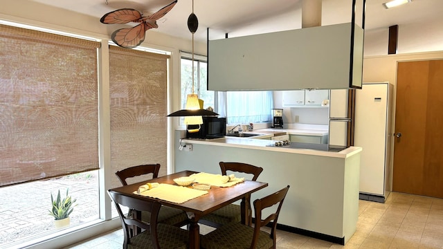 kitchen with sink, hanging light fixtures, white refrigerator, white cabinets, and kitchen peninsula