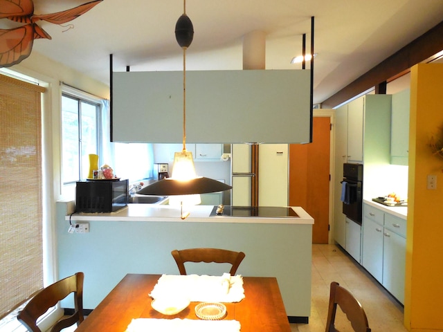 kitchen with hanging light fixtures, light tile patterned floors, black appliances, and kitchen peninsula