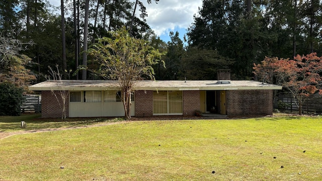 view of front of property with brick siding, a front lawn, and fence