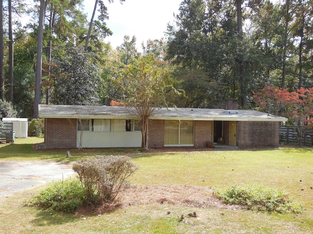 rear view of house with a yard, brick siding, and fence