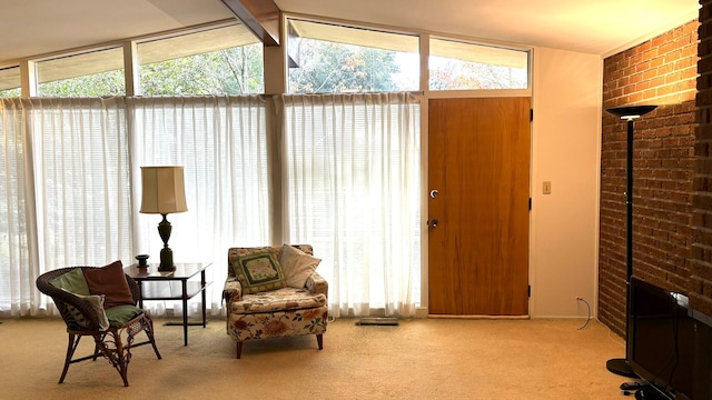 sitting room featuring expansive windows, plenty of natural light, light carpet, and vaulted ceiling with beams