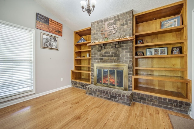208 Mini Farm Rd, Bonneau, SC 29431 - unfurnished living room with a notable chandelier, a brick fireplace, a textured ceiling, wood finished floors, and lofted ceiling