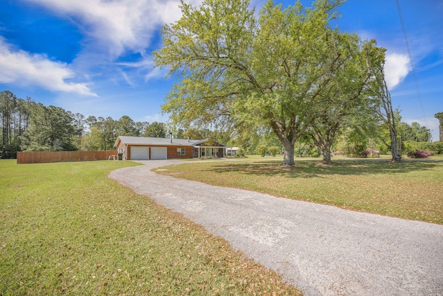 208 Mini Farm Rd, Bonneau, SC 29431 - view of front of home with a garage, gravel driveway, fence, and a front yard