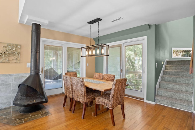 dining space featuring wood-type flooring and a wood stove