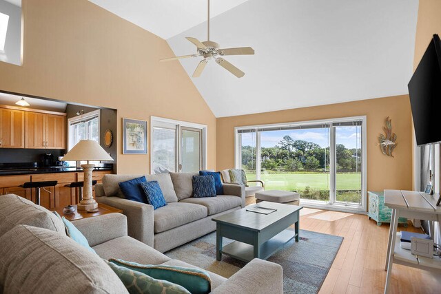 living room with ceiling fan, light hardwood / wood-style flooring, and high vaulted ceiling