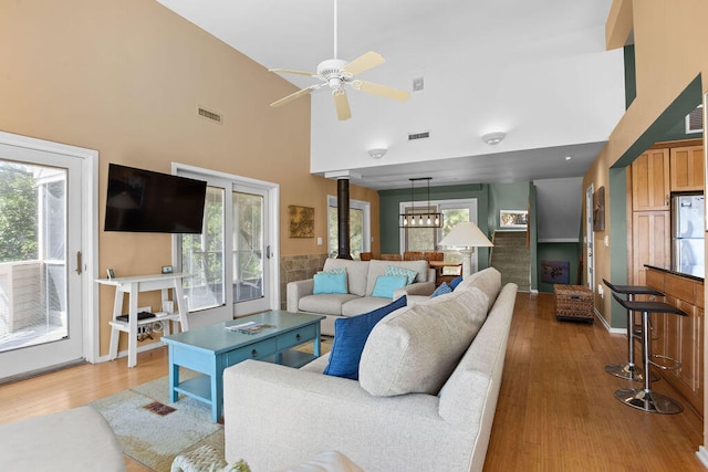 living room with light hardwood / wood-style floors, a towering ceiling, and ceiling fan