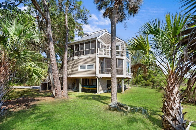 rear view of property featuring a sunroom and a lawn