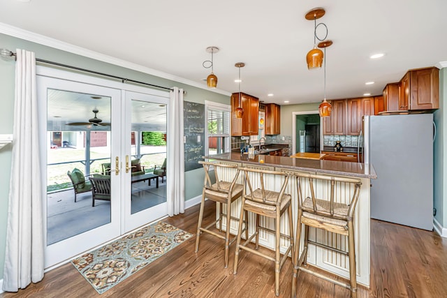 762 Swanson Ave, Charleston, SC 29412 - kitchen featuring freestanding refrigerator, backsplash, a peninsula, crown molding, and brown cabinetry