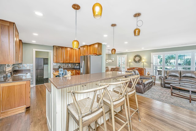 762 Swanson Ave, Charleston, SC 29412 - kitchen with stainless steel fridge with ice dispenser, open floor plan, a center island, decorative backsplash, and light wood-style floors
