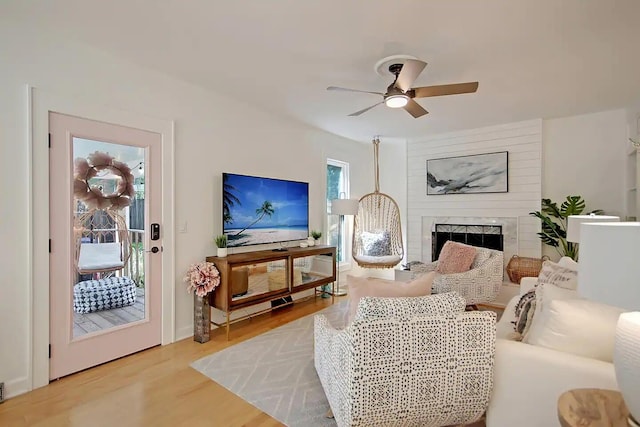 living room featuring light hardwood / wood-style flooring, a large fireplace, and ceiling fan