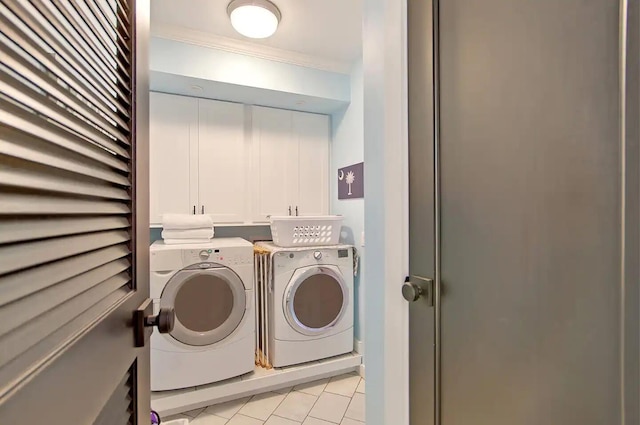 clothes washing area featuring ornamental molding, cabinets, and washer and dryer