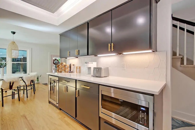 kitchen with wine cooler, tasteful backsplash, stainless steel microwave, pendant lighting, and light wood-type flooring