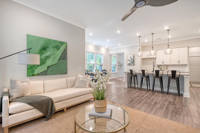 living room featuring light wood-style floors, recessed lighting, crown molding, and a ceiling fan