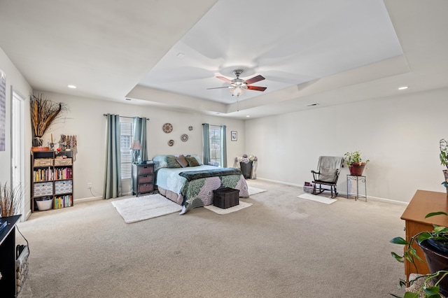 carpeted bedroom featuring a raised ceiling and ceiling fan