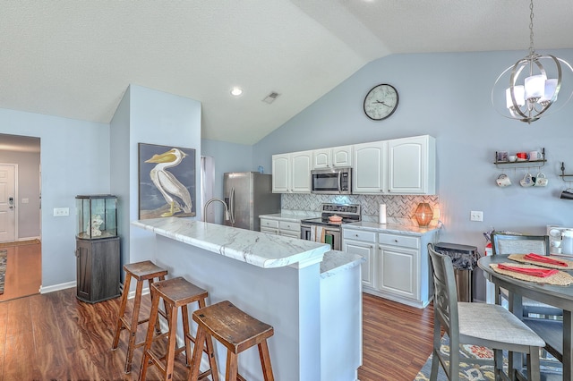 210 Delafield Dr, Summerville, SC 29483 - kitchen featuring appliances with stainless steel finishes, a breakfast bar area, vaulted ceiling, dark wood-style flooring, and white cabinetry