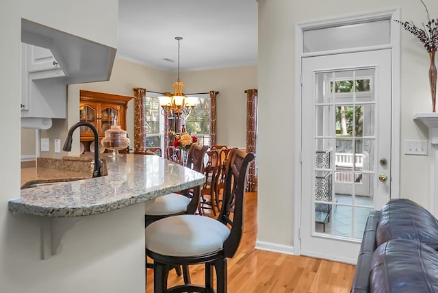 652 Spinner Cir, Mount Pleasant, SC 29464 - kitchen with light wood-style flooring, a chandelier, light stone countertops, white cabinets, and plenty of natural light